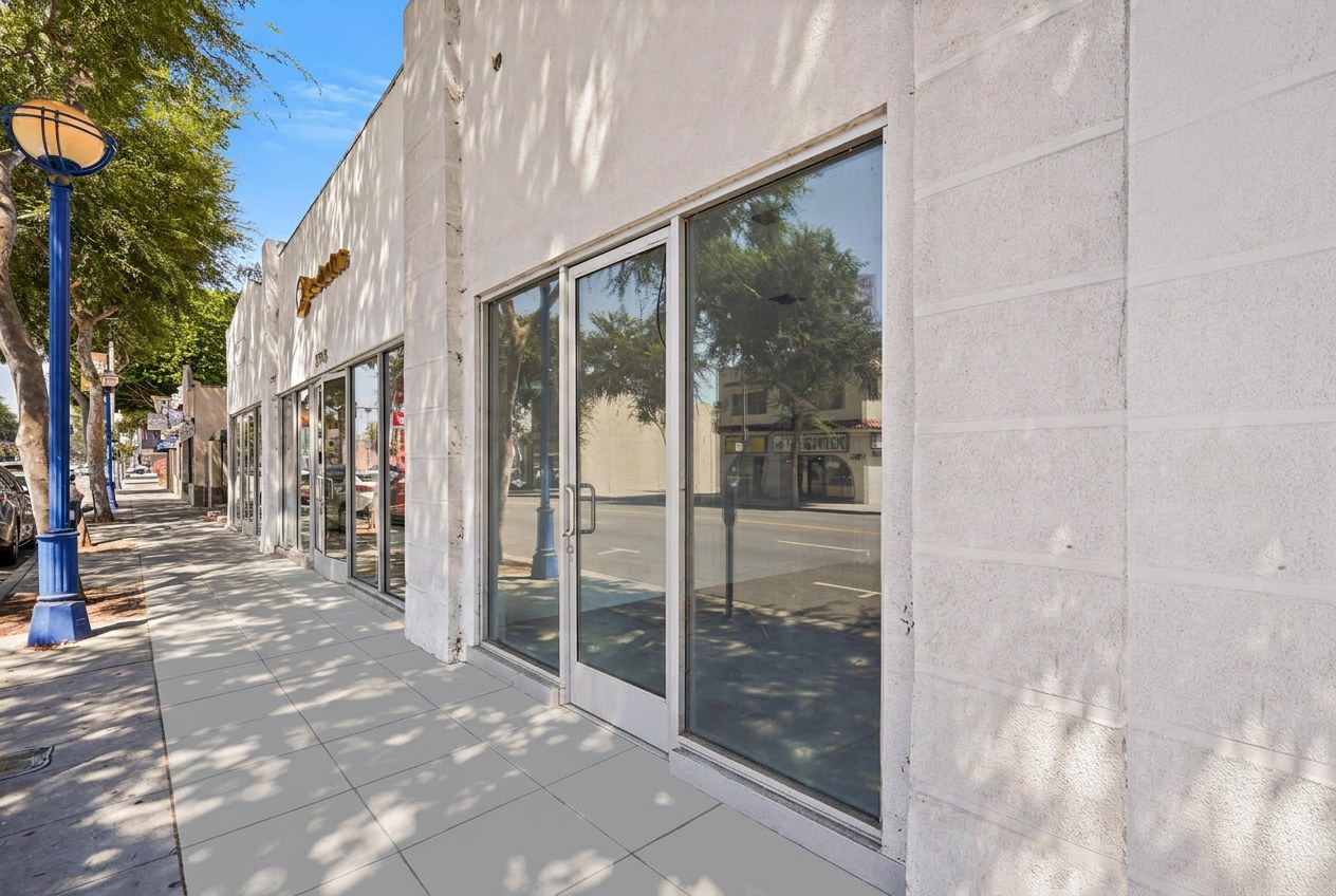 Street-level view of a single-story storefront with floor-to-ceiling glass display windows on Santa Monica Boulevard; illustrative mixed-use property, not a Yelena Mun listing